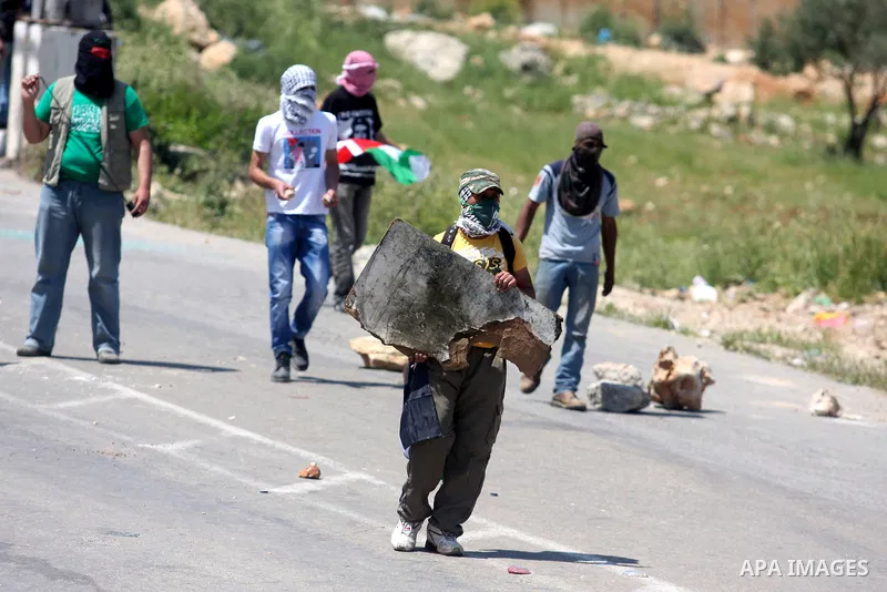 Palestinians hurl stones at an Israeli jeep during clashes with Israeli soldiers at the Bitwonia crossing outside the Israeli military prison of Ofer, on Israel's 64th Independence Day, 26 April 2012. Palestinians staged...