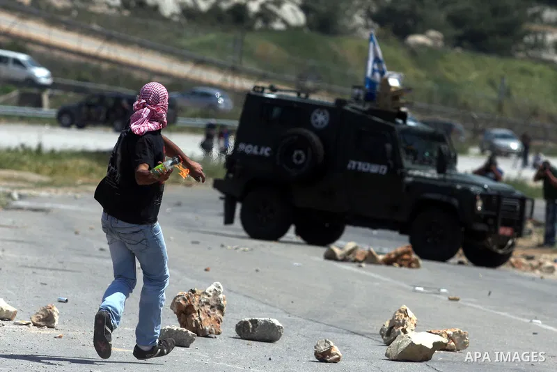Palestinians hurl stones at an Israeli jeep during clashes with Israeli soldiers at the Bitwonia crossing outside the Israeli military prison of Ofer, on Israel's 64th Independence Day, 26 April 2012. Palestinians staged...