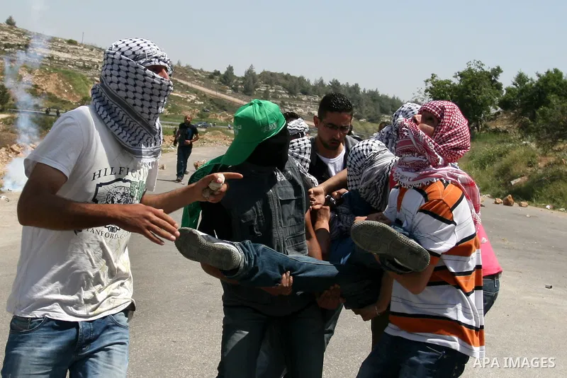 Palestinians carry a wounded demonstrator injured during clashes with Israeli soldiers at the Bitwonia crossing outside the Israeli military prison of Ofer, on Israel's 64th Independence Day, 26 April 2012. Palestinians...