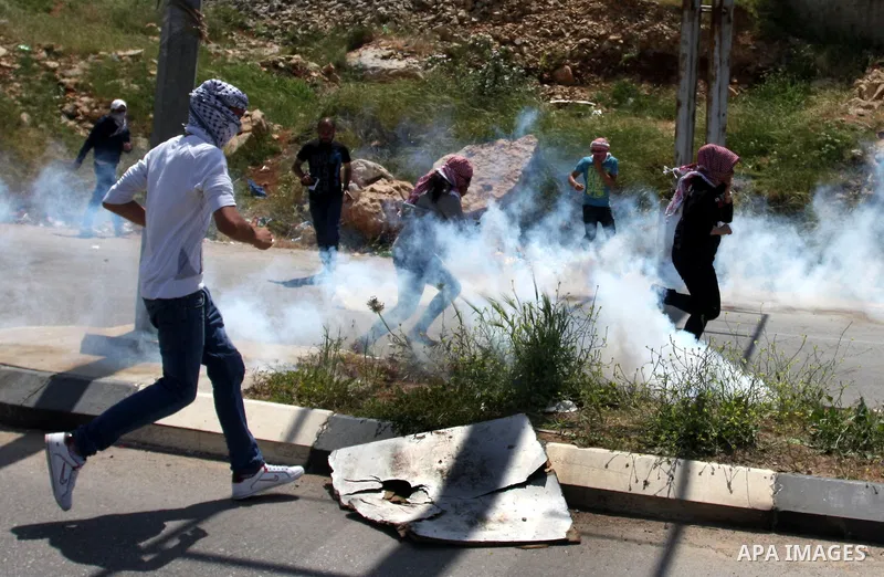 Palestinians hurl stones at an Israeli jeep during clashes with Israeli soldiers at the Bitwonia crossing outside the Israeli military prison of Ofer, on Israel's 64th Independence Day, 26 April 2012. Palestinians staged...