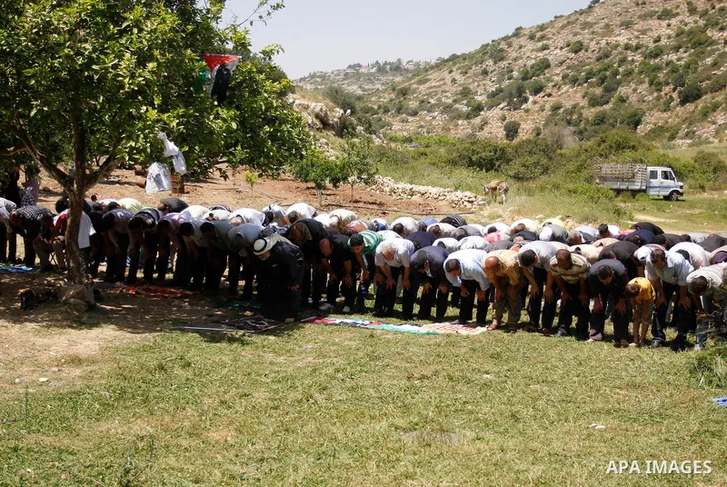 Palestinians pray during a protest against land confiscation by nearby Jewish settlements, Wadi Qana, in the West Bank village Deir Istia , Friday, April 27, 2012 . Photo by Wagdi Eshtayah