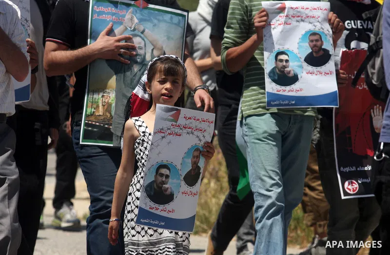 Palestinian protesters hold up banners and portraits during a protest to call for the release of Palestinian prisoners held in Israeli jails in the West Bank village of Nabi Saleh near Ramallah, on April 27, 2012. Photo...