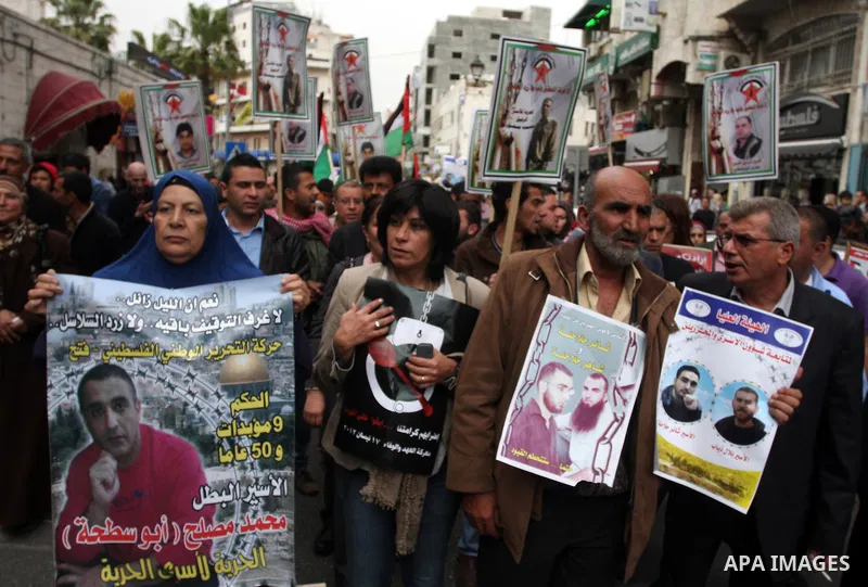 Palestinian protesters hold up banners and portraits of a prisoners jailed in Israel,during a rally in solidarity with prisoners in Israeli jails, in the West Bank city of Ramallah, April 29, 2012.Over the past week, ove...