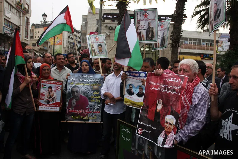 Palestinian protesters hold up banners and portraits of a prisoners jailed in Israel,during a rally in solidarity with prisoners in Israeli jails, in the West Bank city of Ramallah, April 29, 2012.Over the past week, ove...