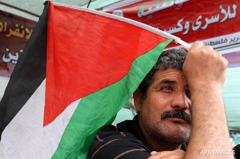 Palestinian man hold up national flag during Sit-in tent to show solidarity with Palestinians prisoners held in Israeli jails in Gaza City on April 30, 2012. At least 1,350 Palestinian prisoners being held in Israel are...