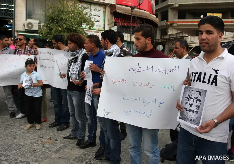 Palestinian journalists hold up banners and portraits of a prisoners jailed in Israel,during a rally in solidarity with prisoners in Israeli jails, in the West Bank city of Ramallah, April 29, 2012.Over the past week, ov...