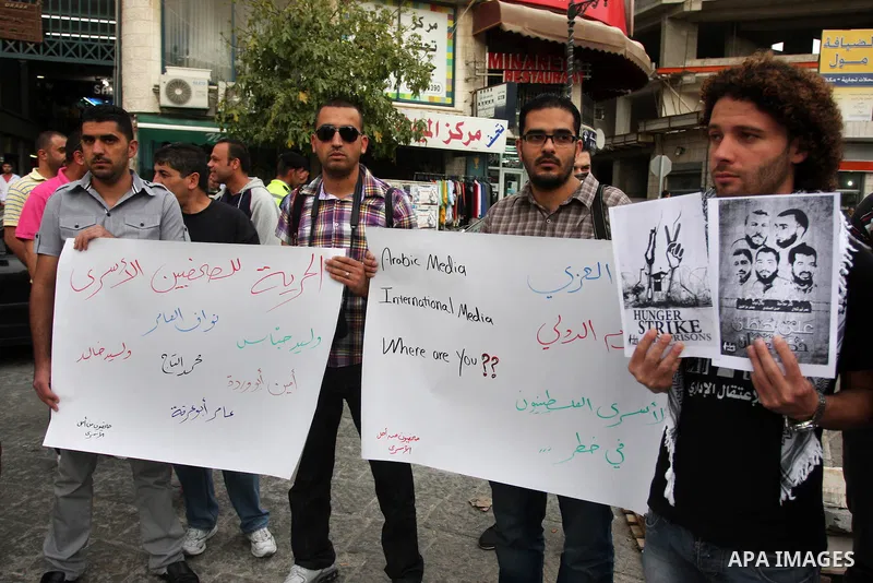 Palestinian journalists hold up banners and portraits of a prisoners jailed in Israel,during a rally in solidarity with prisoners in Israeli jails, in the West Bank city of Ramallah, April 29, 2012.Over the past week, ov...