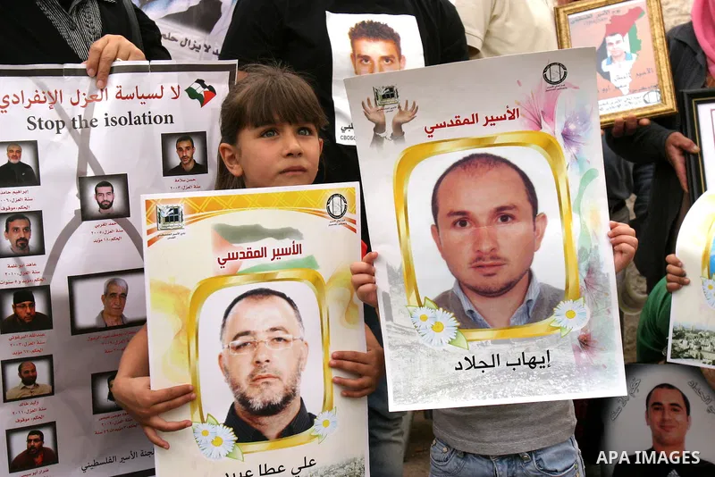 Palestinian protesters hold up banners and portraits of a prisoners jailed in Israel, during a Sit-in held in the neighborhood of Sheikh Jarrah, in front of the Red Cross in the West Bank city of Jerusalem, April 30, 201...