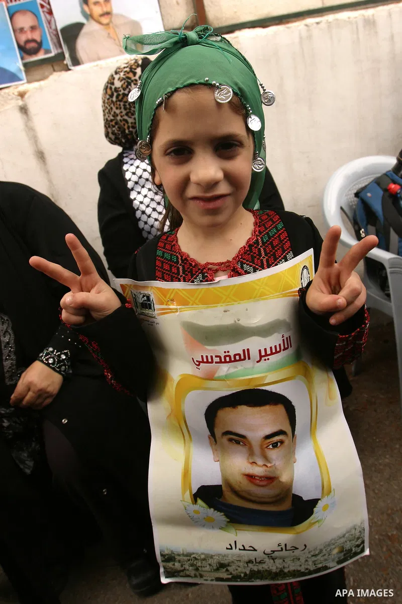 Palestinian child holds up banners and portraits of a prisoners jailed in Israel, during a Sit-in held in the neighborhood of Sheikh Jarrah, in front of the Red Cross in the West Bank city of Jerusalem, April 30, 2012. O...