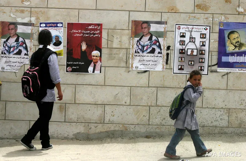 Palestinian school students walk near a Sit-in held in the neighborhood of Sheikh Jarrah, in front of the Red Cross in the West Bank city of Jerusalem, April 30, 2012. Over the past week, over 1,350 Palestinian prisoners...