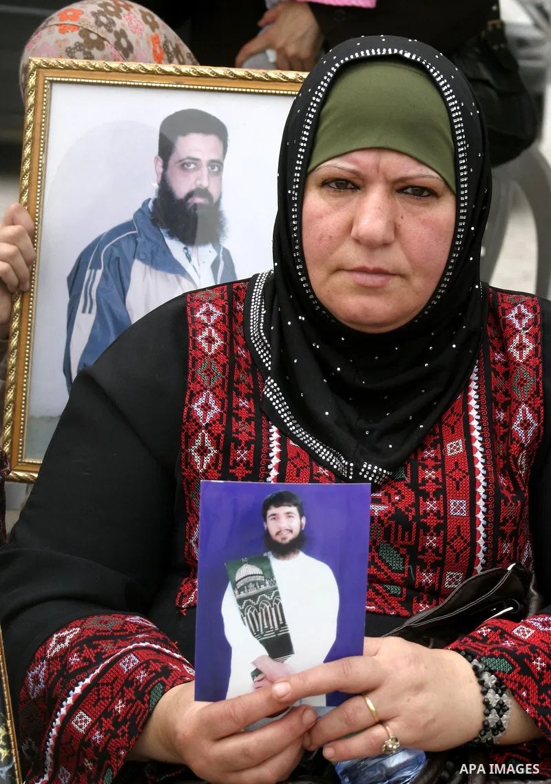 Palestinian woman holds up banners and portraits of a prisoners jailed in Israel, during a Sit-in held in the neighborhood of Sheikh Jarrah, in front of the Red Cross in the West Bank city of Jerusalem, April 30, 2012. O...