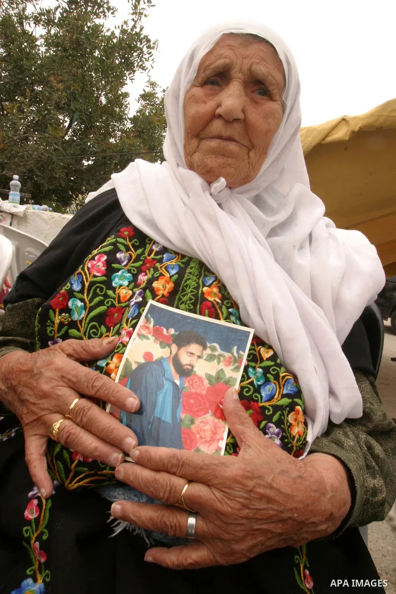 Palestinian old woman holds up banners and portraits of a prisoners jailed in Israel, during a Sit-in held in the neighborhood of Sheikh Jarrah, in front of the Red Cross in the West Bank city of Jerusalem, April 30, 201...