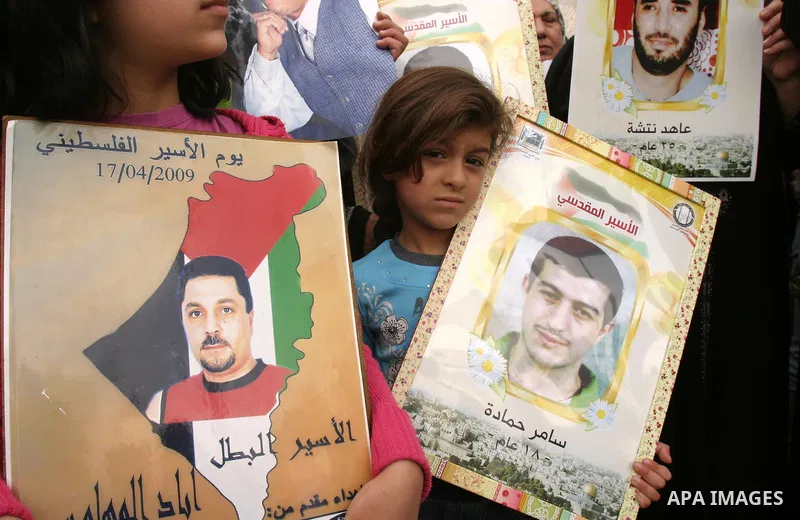 Palestinian children hold up banners and portraits of a prisoners jailed in Israel, during a Sit-in held in the neighborhood of Sheikh Jarrah, in front of the Red Cross in the West Bank city of Jerusalem, April 30, 2012....