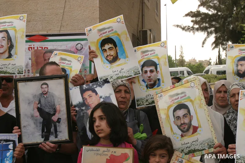 Palestinian protesters hold up banners and portraits of a prisoners jailed in Israel, during a Sit-in held in the neighborhood of Sheikh Jarrah, in front of the Red Cross in the West Bank city of Jerusalem, April 30, 201...