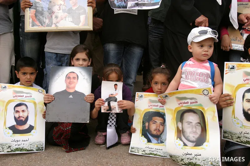 Palestinian children hold up banners and portraits of a prisoners jailed in Israel, during a Sit-in held in the neighborhood of Sheikh Jarrah, in front of the Red Cross in the West Bank city of Jerusalem, April 30, 2012....