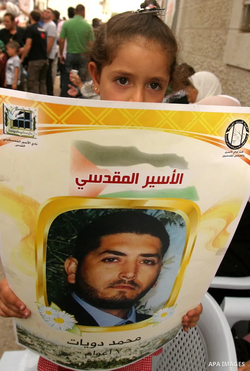 Palestinian child holds up banners and portraits of a prisoners jailed in Israel, during a Sit-in held in the neighborhood of Sheikh Jarrah, in front of the Red Cross in the West Bank city of Jerusalem, April 30, 2012. O...