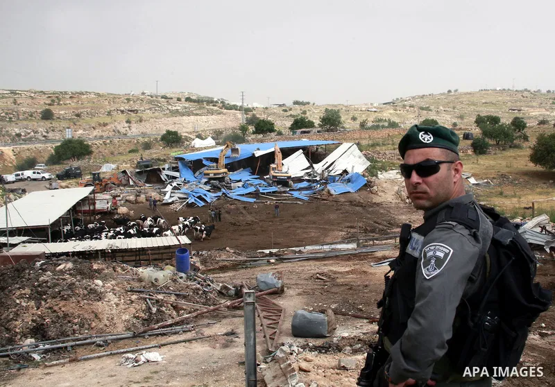 Israeli soldiers surround a bulldozer as it destroys a Palestinian farm to cows in the West Bank city of Hebron, May. 01, 2012. Reports state that tensions rose as Palestinian homes were destroyed by Israeli authorities...