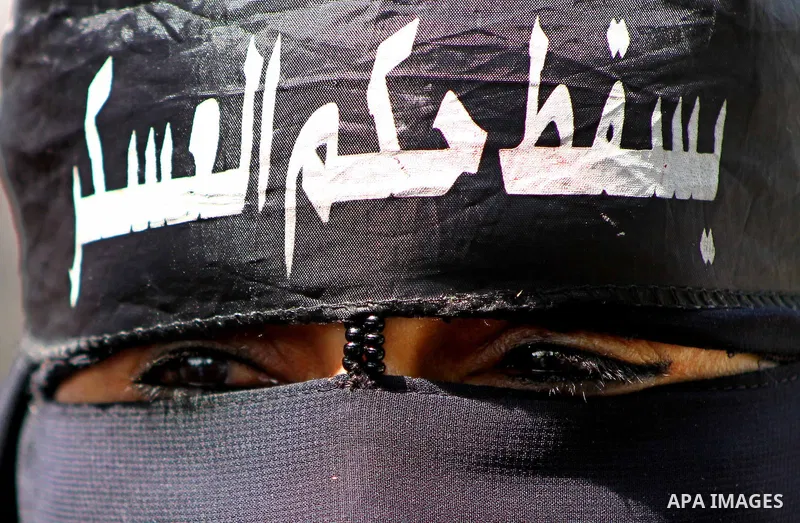An Egyptian woman wears the Niqab with Arabic writing that reads, "down with military rule," at the road leading to the Ministry of Defense, in Cairo. Photo by Ashraf Amra