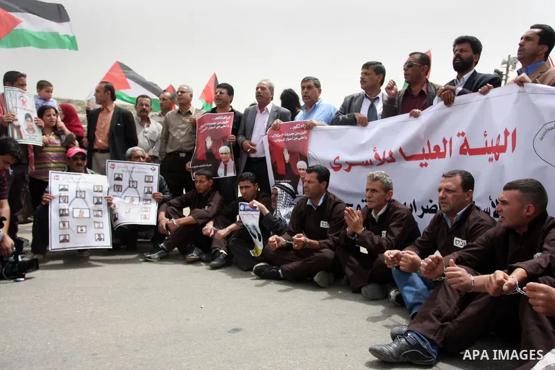 Palestinian protesters gesture with their hands chained during a protest outside Ofer prison near the West Bank city of Ramallah May 1, 2012, in solidarity with hunger striking Palestinian prisoners. The hunger strike ag...