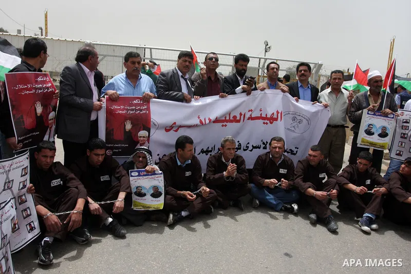 Palestinian protesters gesture with their hands chained during a protest outside Ofer prison near the West Bank city of Ramallah May 1, 2012, in solidarity with hunger striking Palestinian prisoners. The hunger strike ag...