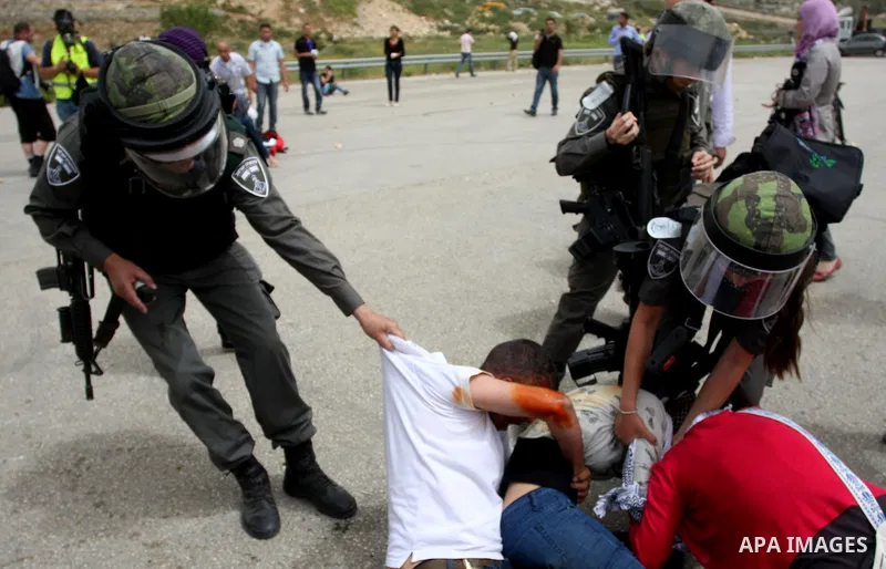 Palestinian protesters who were hit with pepper spray by Israeli border police, lie on the ground as they try to prevent Israeli troops from detaining one of them, during clashes outside Ofer prison near the West Bank ci...
