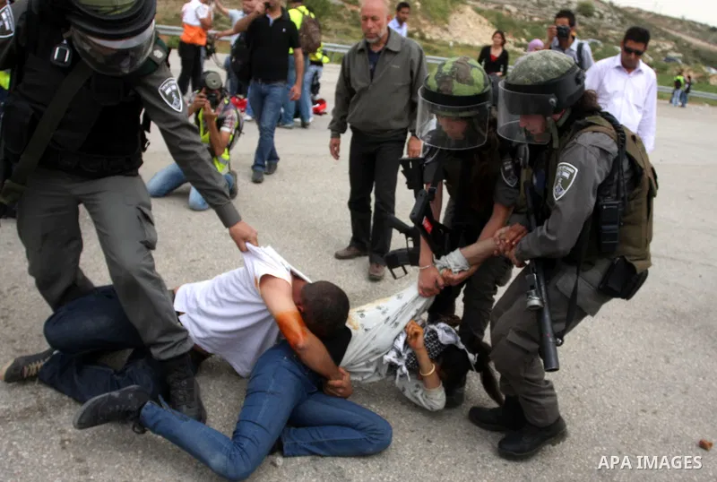 Palestinian protesters who were hit with pepper spray by Israeli border police, lie on the ground as they try to prevent Israeli troops from detaining one of them, during clashes outside Ofer prison near the West Bank ci...