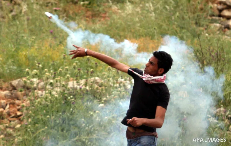 Palestinian protesters return a tear gas to Israeli troops during a demonstration outside Ofer military prison near the West Bank city of Ramallah on May 1, 2012 in a show of support for prisoners held in Israeli jails....