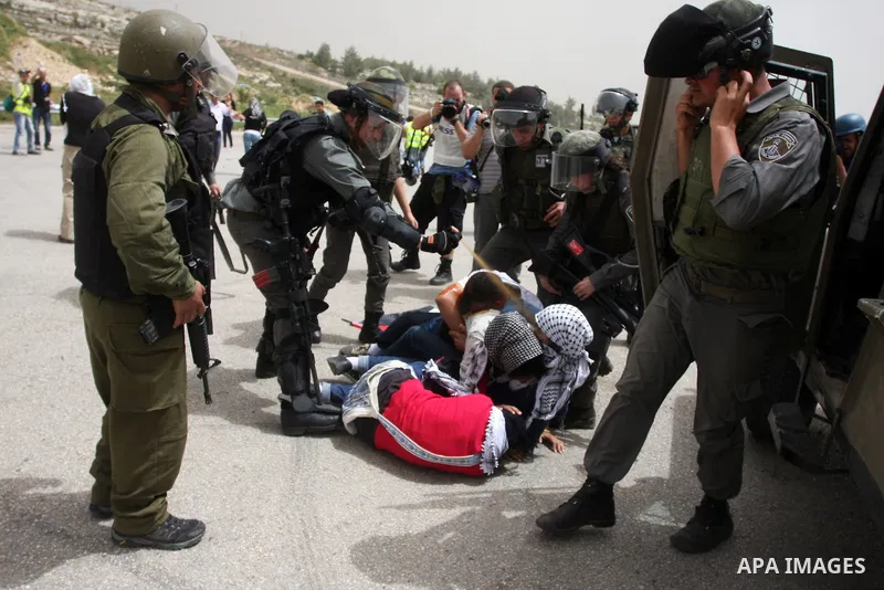Palestinian protesters who were hit with pepper spray by Israeli border police, lie on the ground as they try to prevent Israeli troops from detaining one of them, during clashes outside Ofer prison near the West Bank ci...