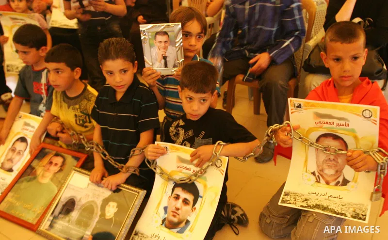 Palestinian children hold up banners and portraits of a prisoners jailed in Israel, during a Sit-in held in the West Bank city of Jerusalem, May 01, 2012. Over the past week, over 1,350 Palestinian prisoners have begun a...