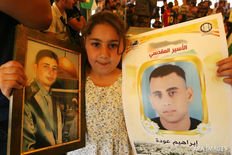 Palestinian child hold up banners and portraits of a prisoners jailed in Israel, during a Sit-in held in the West Bank city of Jerusalem, May 01, 2012. Over the past week, over 1,350 Palestinian prisoners have begun an o...