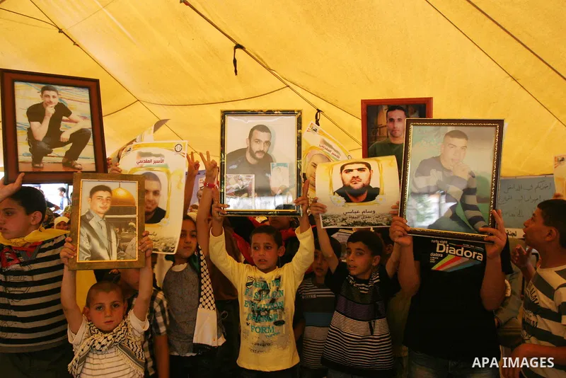 Palestinian children hold up banners and portraits of a prisoners jailed in Israel, during a Sit-in held in the West Bank city of Jerusalem, May 01, 2012. Over the past week, over 1,350 Palestinian prisoners have begun a...