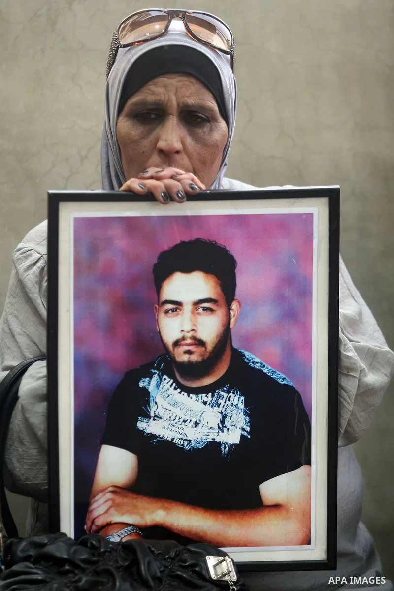 Palestinian woman holds up portrait of a prisoners jailed in Israel,during a rally in solidarity with prisoners in Israeli jails,outside the Red Cross building in the West Bank city of Ramallah on May 1, 2012. Photo by I...