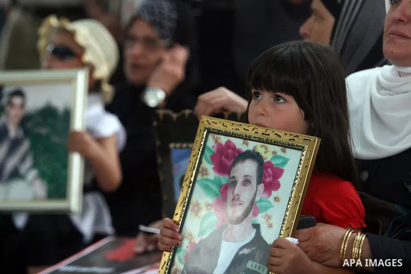 Palestinian child holds up portrait of a prisoners jailed in Israel,during a rally in solidarity with prisoners in Israeli jails,outside the Red Cross building in the West Bank city of Ramallah on May 1, 2012. Photo by I...