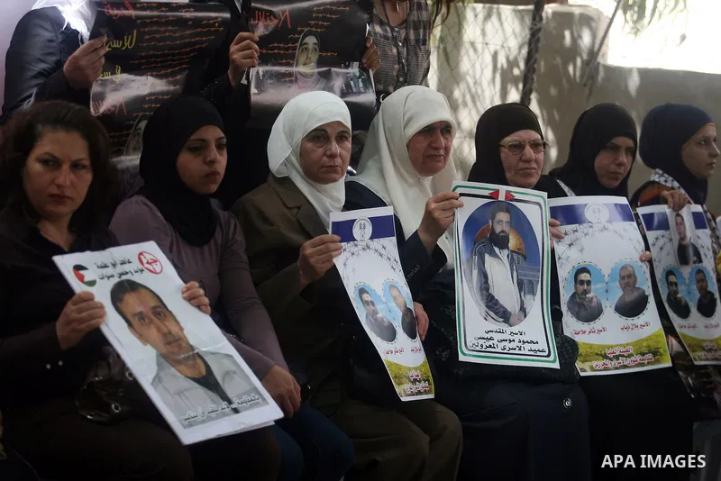 Palestinian protesters hold up banners and portraits of a prisoners jailed in Israel,during a rally in solidarity with prisoners in Israeli jails,outside the Red Cross building in the West Bank city of Ramallah on May 1,...