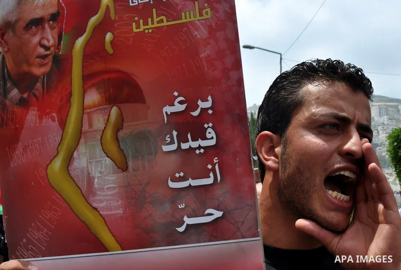 Palestinian protesters hold up banners and portraits of a prisoners jailed in Israel, during a rally in solidarity with prisoners in Israeli jails, in the West Bank city of Nablus on May 2, 2012. Photo by Nedal Eshtayah