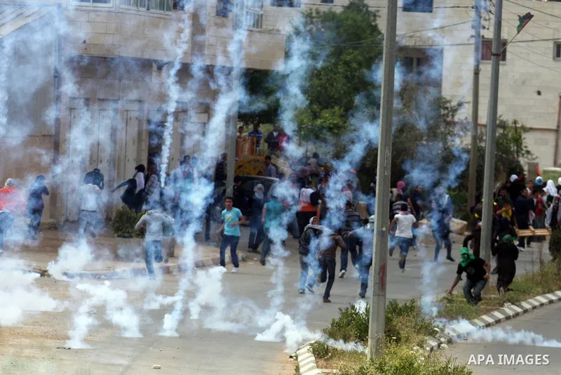 Tear gas fired by Israeli troops falls near Palestinian stone-throwers during clashes next to the Israeli military prison of Ofer, near Beitunia, West Bank, 02 May 2012. The protesters were protesting in solidarity with...