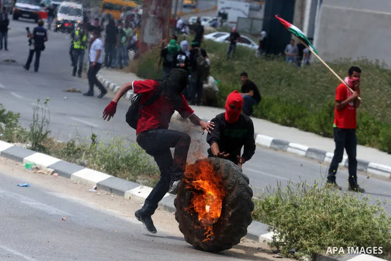 A Palestinian protester kicks a burning tyre towards Israeli troops during clashes next to the Israeli military prison of Ofer, near Beitunia, West Bank, 02 May 2012. The protesters were protesting in solidarity with the...