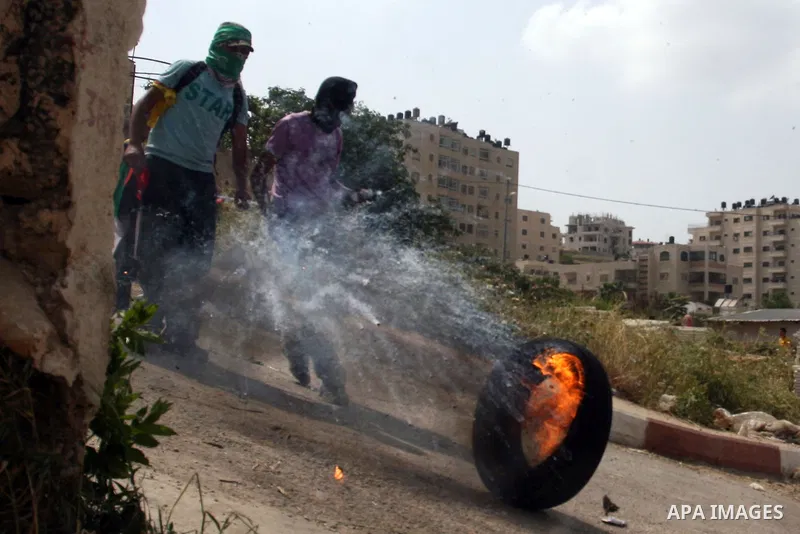 A Palestinian protester kicks a burning tire towards Israeli troops during clashes next to the Israeli military prison of Ofer, near Beitunia, West Bank, 03 May 2012. following a demonstration in solidarity with Palestin...