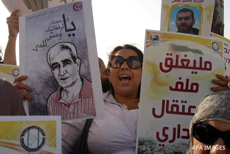Palestinian protesters hold up banners and portraits of a prisoners jailed in Israel, during a rally next to Al-Ramle Prison, near Tel Aviv, Thursday, May 3, 2012. A Palestinian rights group said recently that half of ab...