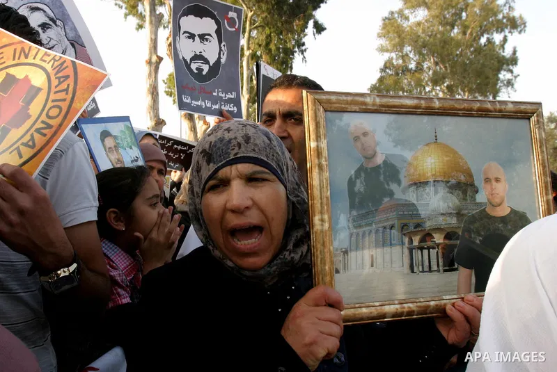 Palestinian protesters hold up banners and portraits of a prisoners jailed in Israel, during a rally next to Al-Ramle Prison, near Tel Aviv, Thursday, May 3, 2012. A Palestinian rights group said recently that half of ab...