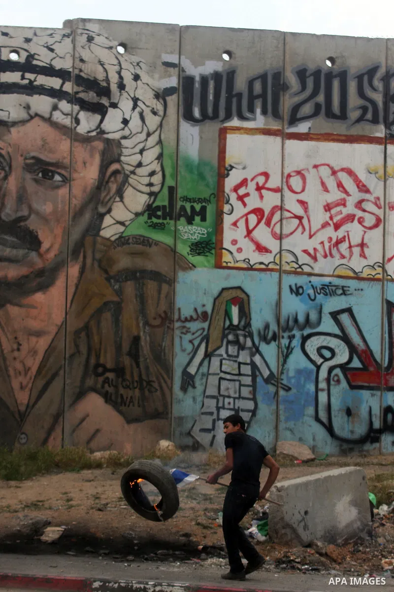 A Palestinian protester kicks a burning tire towards Israeli troops at the Qalandia crossing in the occupied West Bank during a demonstration on May 4, 2012 in solidarity with Palestinian prisoners on hunger strike to pr...