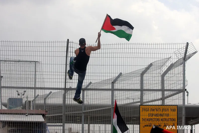 A Palestinian man hold national flag at the Qalandia crossing in the occupied West Bank during a demonstration on May 4, 2012 in solidarity with Palestinian prisoners on hunger strike to protest Israel's use of administr...