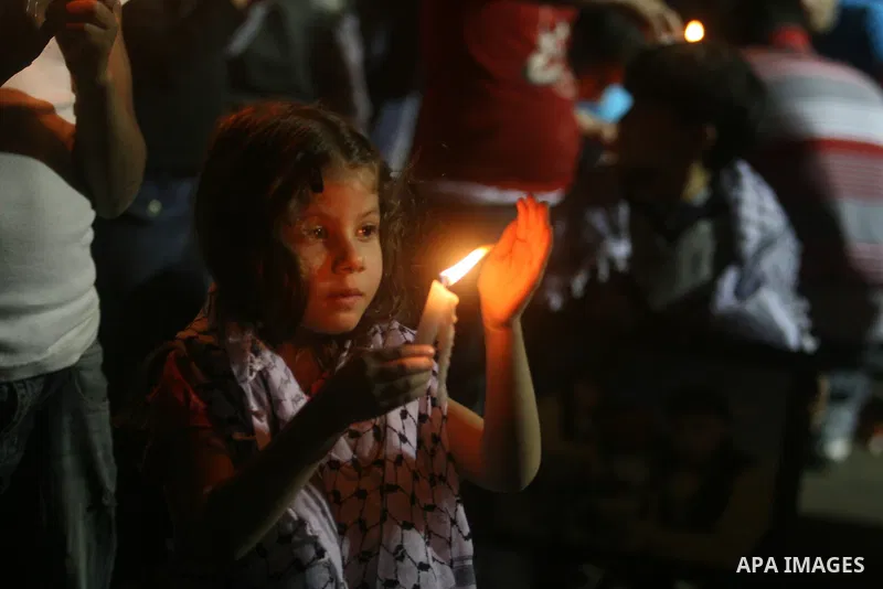 Palestinian children light candles, during a rally outside a tent solidarity with prisoners who have been waging a hunger strike in Israeli jails, to protest Israel's use of administrative detention orders, in the West B...