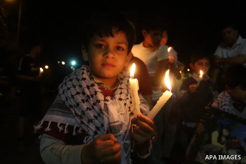 Palestinian children light candles, during a rally outside a tent solidarity with prisoners who have been waging a hunger strike in Israeli jails, to protest Israel's use of administrative detention orders, in the West B...