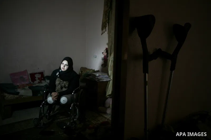 Jamela Al-Habash, a 17-year-old Palestinian girl who lost her legs, sits in a wheelchair waiting for her brothers to help her leaving her family's home in the Jabaliya refugee camp in the Gaza Strip, 03 May 2012. Al-Haba...