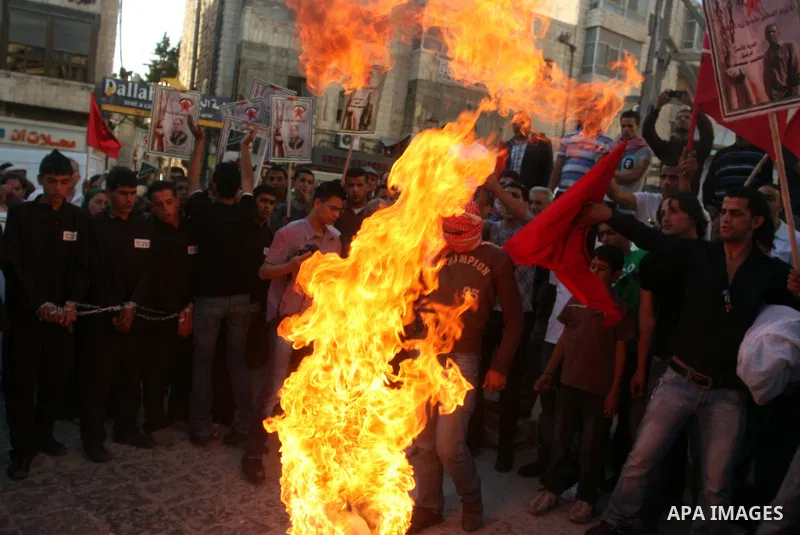 Palestinians burn Israeli flags during a support rally for Palestinian prisoners on hunger strike, in the West Bank city of Ramallah, May 6, 2012. Photo by Issam Rimawi