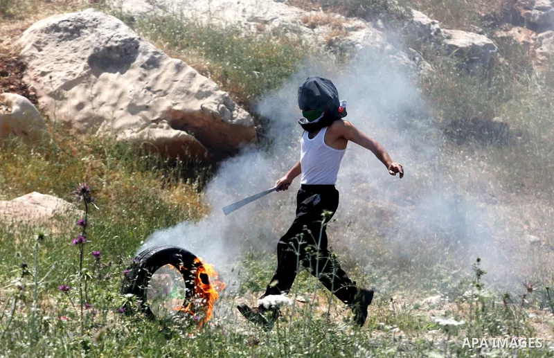 A Palestinian youth kicks a flaming tire during clashes with Israeli soldiers outside the Ofer Prison close to the West Bank city of Ramallah, following a march in support of Palestinian prisoners of on hunger strike whi...