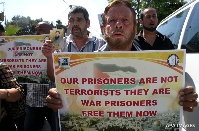 Palestinian protesters hold slogans and portraits of Palestinian prisoners, held in Israeli jails, during a demonstration in east Jerusalem on May 7, 2012 in solidarity with the prisoners. At least 1,550 imprisoned Pales...