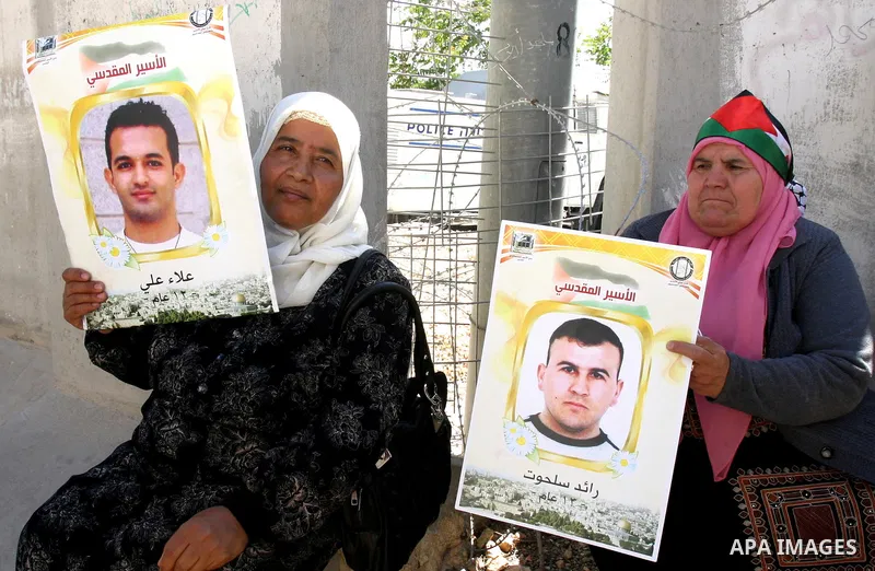 Palestinian protesters hold slogans and portraits of Palestinian prisoners, held in Israeli jails, during a demonstration in east Jerusalem on May 7, 2012 in solidarity with the prisoners. At least 1,550 imprisoned Pales...