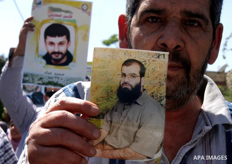 Palestinian protesters hold slogans and portraits of Palestinian prisoners, held in Israeli jails, during a demonstration in east Jerusalem on May 7, 2012 in solidarity with the prisoners. At least 1,550 imprisoned Pales...
